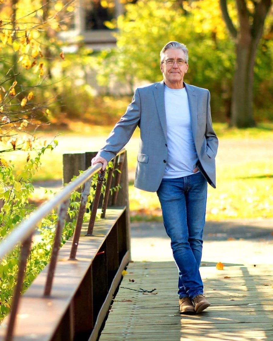 Gregory Long, results and life coach, walking across a wooden footbridge in autumn